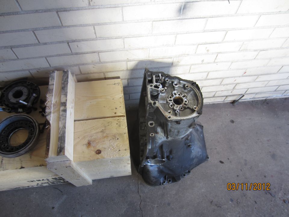 Transmission housing and some circular parts next to a wooden crate. Date stamp 03/11/2012