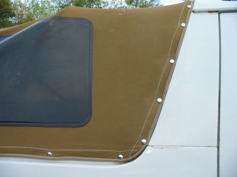 1992 Ford Bronco - Close-up of a tan soft top with a dark window, attached to the white body of a vehicle.