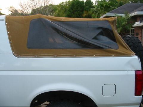 1992 Ford Bronco - This 1992 Ford Bronco features a tan soft top with dark tinted windows, seen from the side.