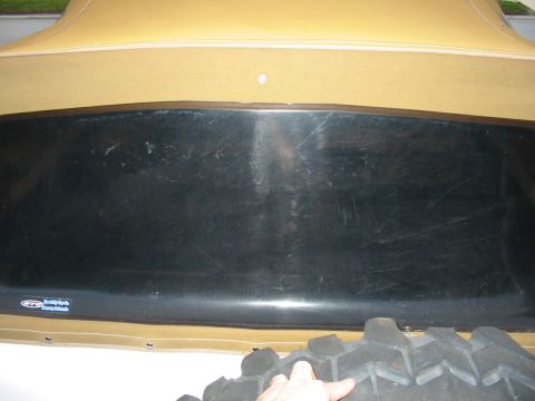 1992 Ford Bronco - A close-up view shows the tan soft top and a portion of the vehicle's body, along with a tire tread.