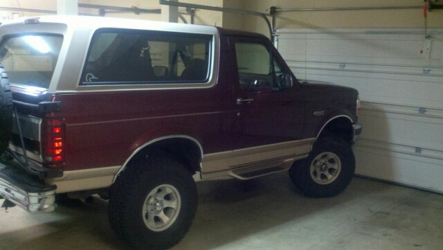 Maroon and tan SUV, rear quarter view. Spare tire mounted on rear door