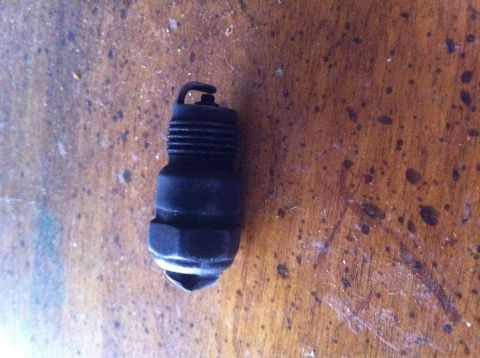 1990 Ford Bronco - A single spark plug is shown on a textured wooden background.