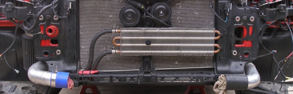 Front view of an oil cooler mounted in front of a radiator, with associated hoses and mounting brackets