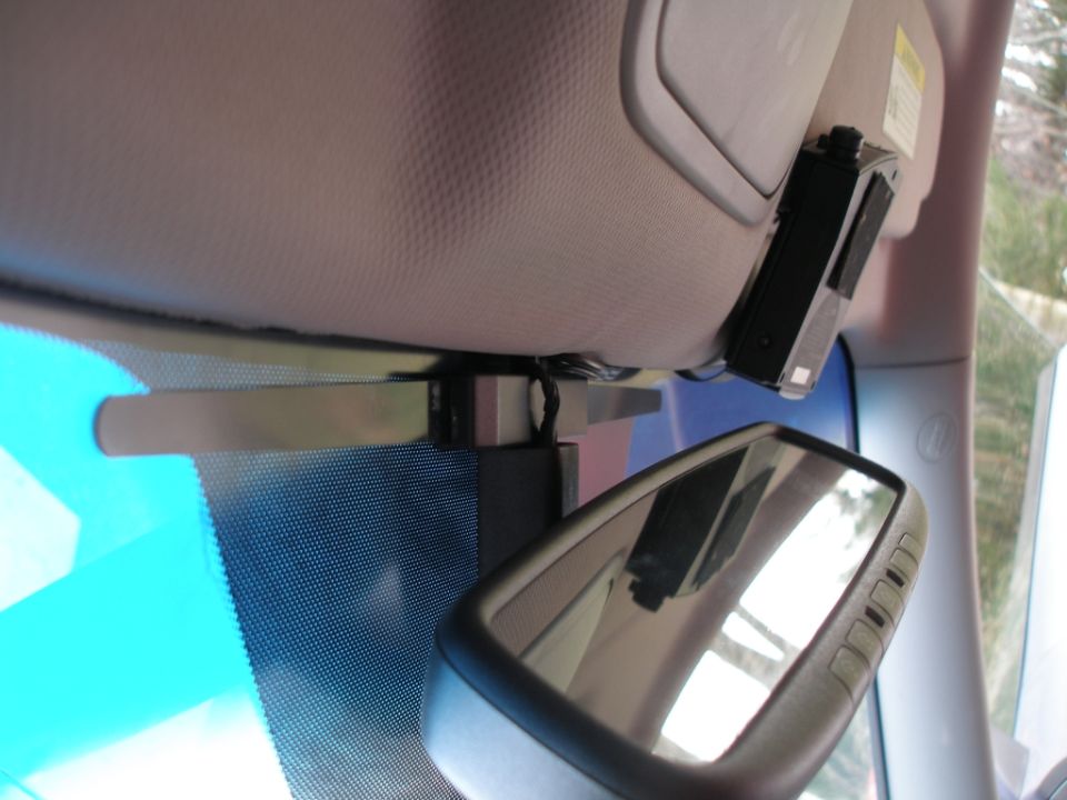 Interior rearview mirror and sun visor with a black electronic device attached