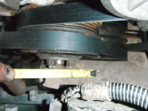 1988 Ford Bronco - Close-up view of engine pulleys and a belt, with a tape measure indicating a measurement.