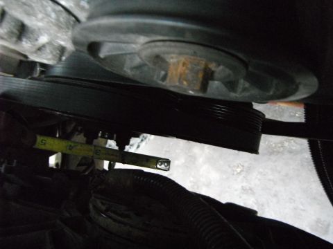 1988 Ford Bronco - Close-up of an engine pulley and belt, with a tape measure for scale.