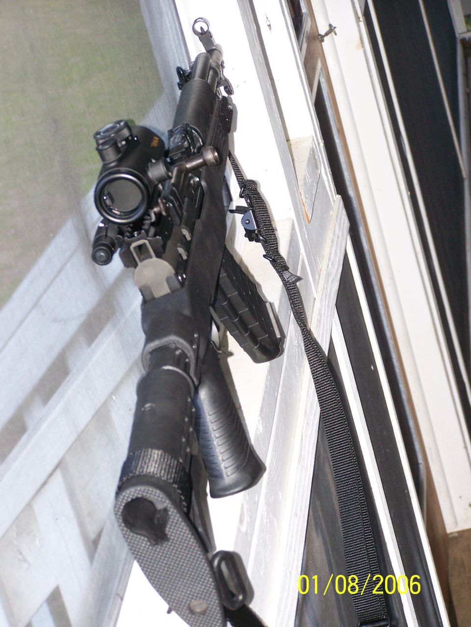 Rifle with scope and sling, mounted on a white railing