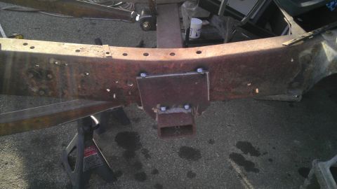 1987 Ford Ranger - Close-up of a rusty vehicle frame showing a recently installed hitch receiver, supported by jack stands on asphalt.