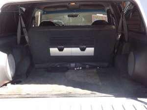 1993 Ford Bronco - Interior view of a white SUV's cargo area, showing folded rear seats and audio equipment.