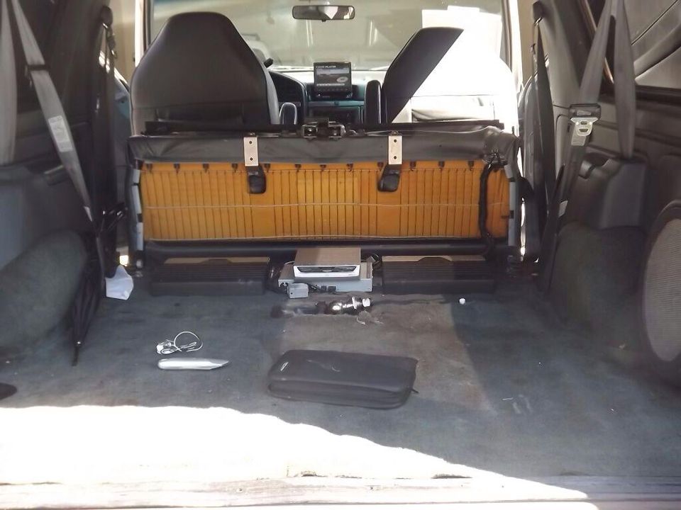 Interior view of a van or SUV with rear seats folded down, showing a cargo area with some electronics and bags