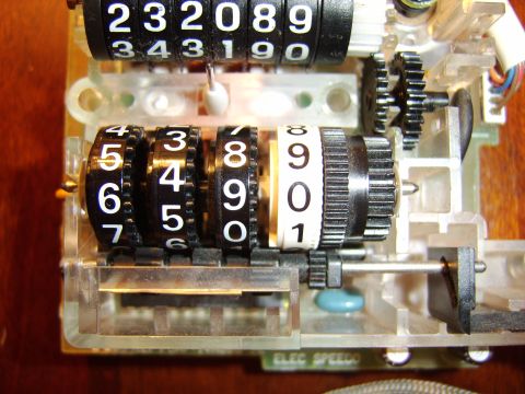 1996 Mercury Grand Marquis - Close-up view of an odometer mechanism, showing the numbered rollers and internal gears.