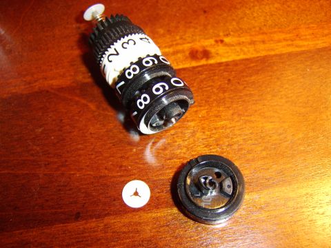 1996 Mercury Grand Marquis - Disassembled odometer reset knob and associated parts on a wooden table.
