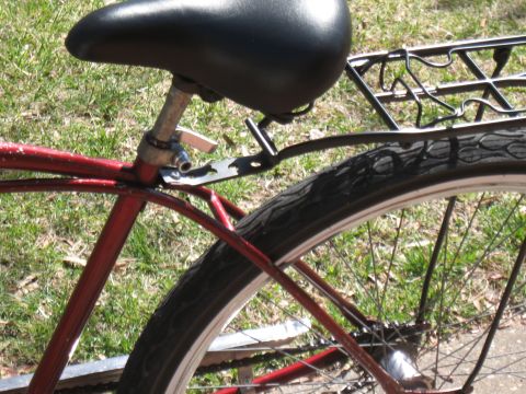 1994 Ford Bronco - The rear section of a red bicycle is shown with a black seat and a metal luggage rack.