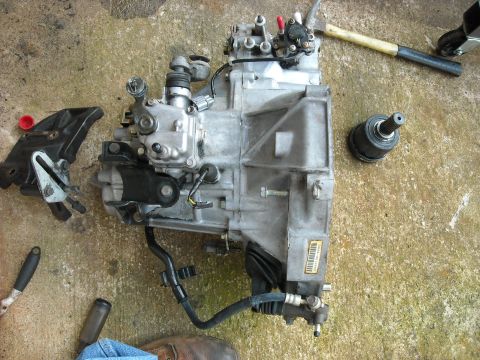 1979 Ford F-150 - Car transmission and parts laid out on a concrete surface, possibly for repair or replacement.