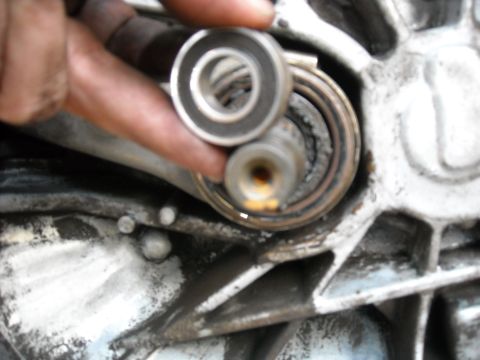 1979 Ford F-150 - A hand holds a bearing above a greasy, worn shaft assembly, suggesting a mechanical repair or inspection.