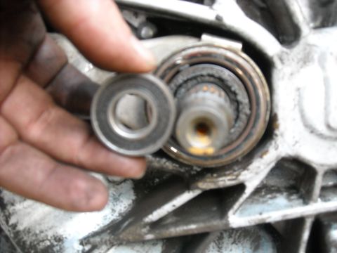 1979 Ford F-150 - A hand holds a bearing, preparing to replace a worn bearing on a shaft. This part is likely from a vehicle's drivetrain.