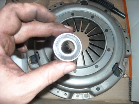 1979 Ford F-150 - A hand holds a bearing over a clutch pressure plate, likely for a vehicle repair.