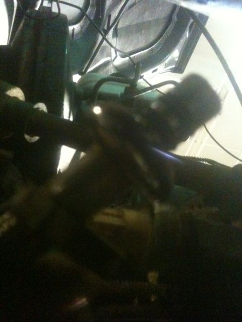 1993 Ford Bronco - View of various engine bay components, including hoses and wiring, in a dark setting.