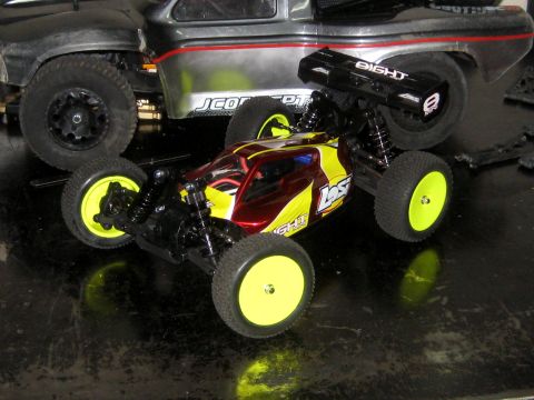 1996 Ford Bronco - A close-up view of two remote control vehicles, a buggy and a truck, on a dark surface.