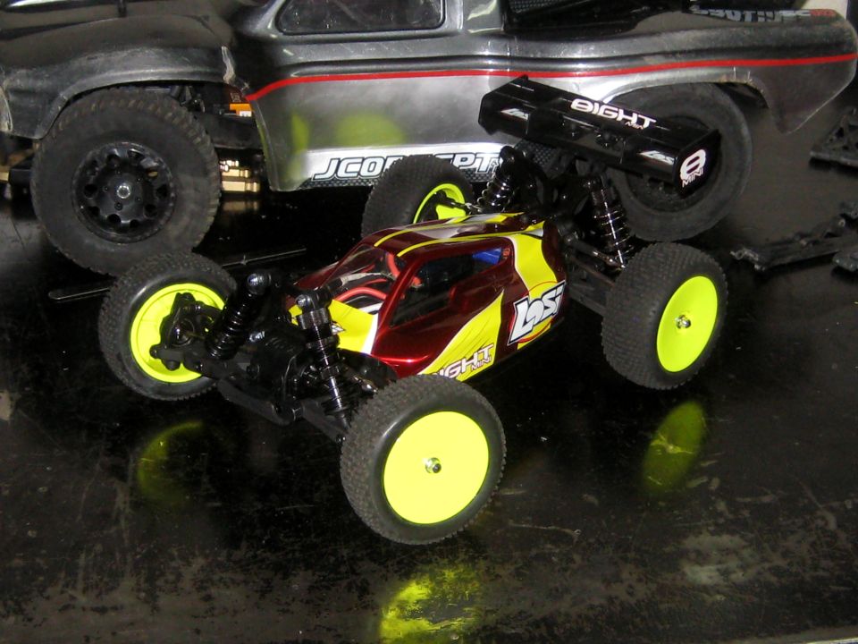 Two remote control vehicles, a red and yellow buggy in front and a silver and black truck behind