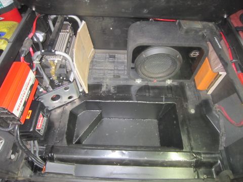 2008 Jeep Wrangler - Aftermarket electronics installed in a vehicle's rear storage compartment, including a subwoofer and air compressor.