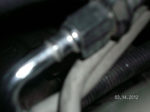 1996 Ford Bronco - Close-up of a chrome fuel fitting with a hex nut, adjacent to black corrugated tubing and a white cable.