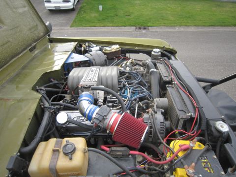1974 Ford Bronco - The engine bay of a Ford Bronco shows a 5.0 HO engine with various aftermarket modifications.
