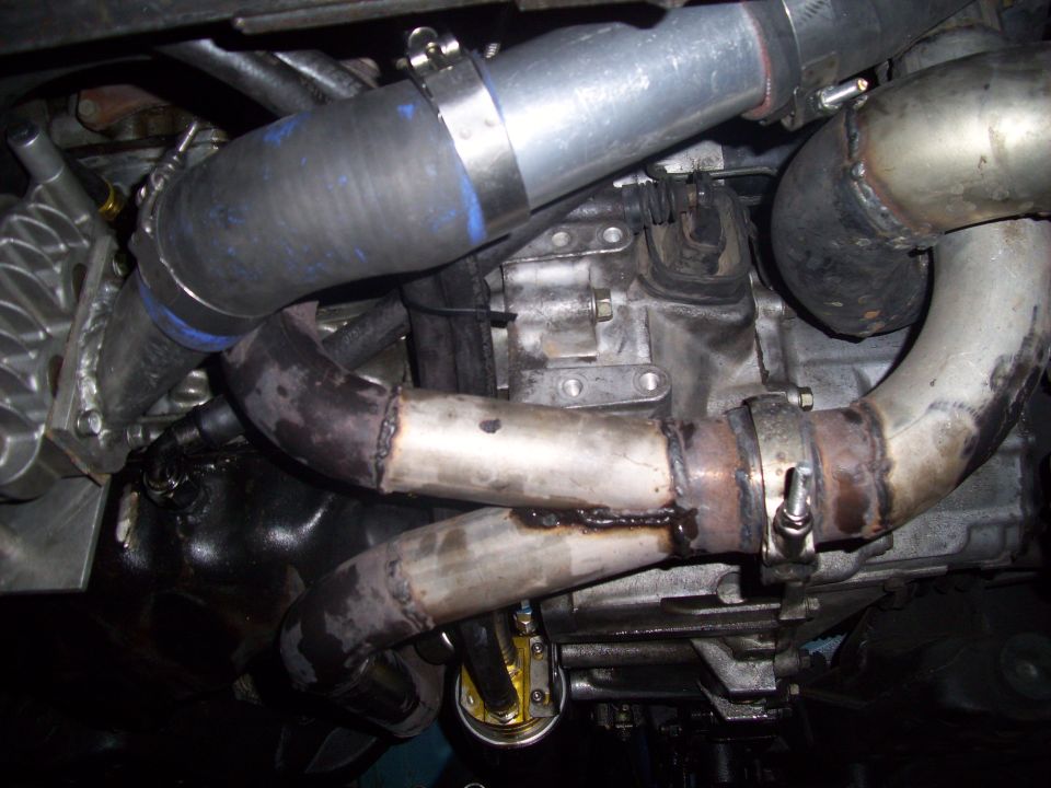 Close-up of turbo plumbing and engine components, showing hoses and exhaust pipes