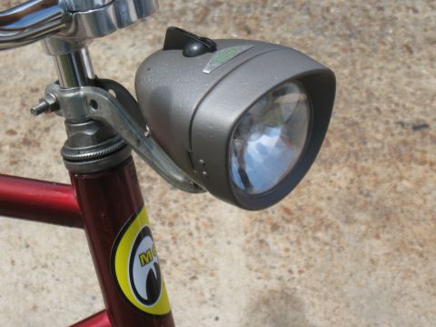 1994 Ford Bronco - A vintage bicycle headlight with a visible green sticker is mounted on the handlebars of a red bicycle.