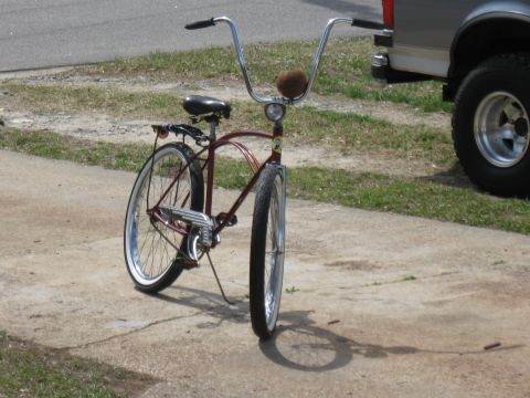 1994 Ford Bronco - Cruiser bicycle with chrome handlebars and whitewall tires parked on concrete next to a truck.