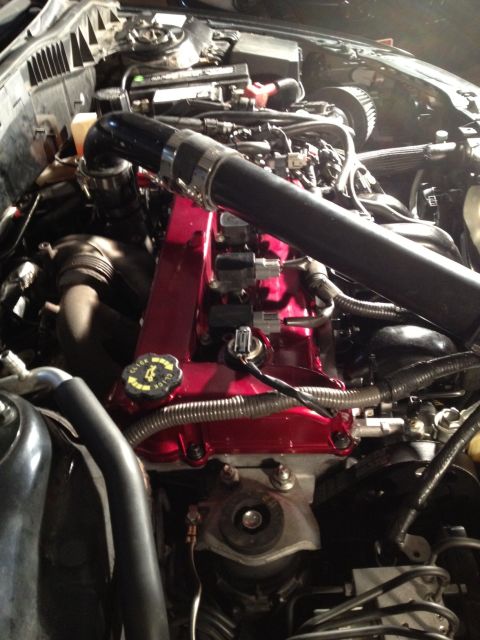 1987 Ford Bronco - The engine bay of a car, red painted valve covers and various hoses and wires.