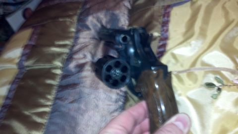 1988 Chevrolet Suburban - A revolver with a wooden grip is held over a patterned fabric surface.