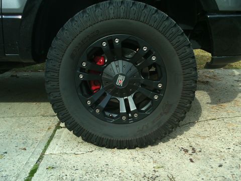 2008 Ford F-150 - Close-up of a black aftermarket wheel with red brake caliper and aggressive tire tread on a vehicle.