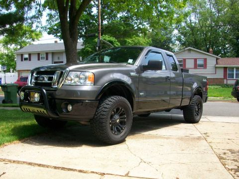 2008 Ford F-150 - Gray Ford F-150 pickup truck with aftermarket bull bar and large tires parked on a driveway.