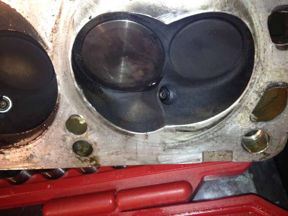 Close-up of an engine cylinder head with two large valves and a spark plug hole