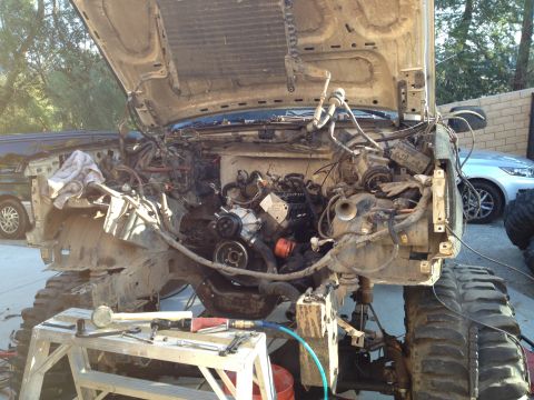 1992 Ford Bronco - Disassembled engine bay with the hood open, tools laid out on a workbench, and another vehicle visible in the background.