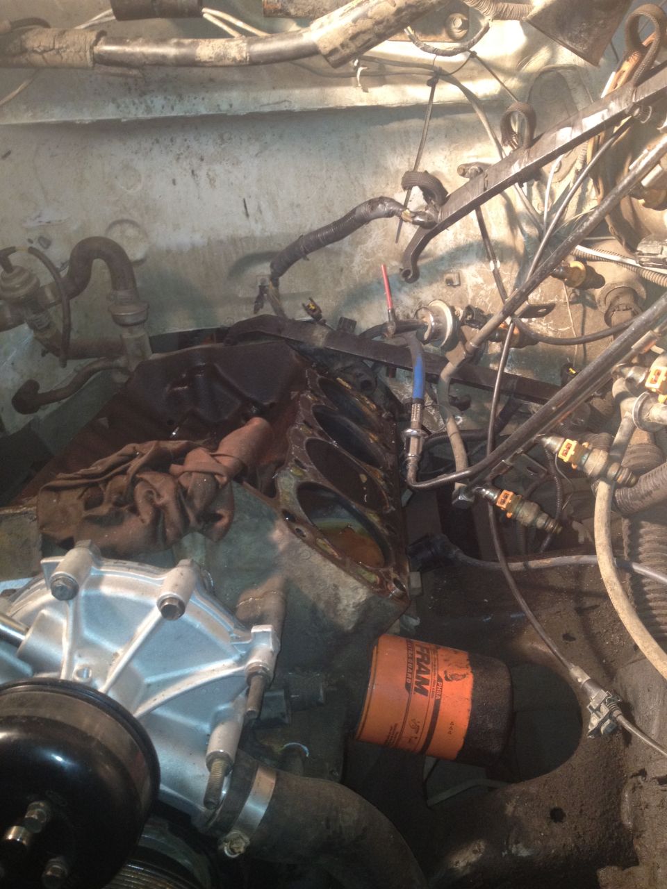 Engine block with oil filter and water pump, disassembled engine components, hoses, and wiring