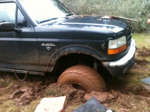 1994 Ford F-150 - A Ford truck is stuck in thick mud, with one tire completely submerged.