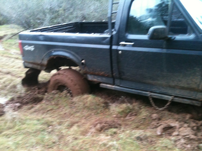 Side view of a dark 1994 Ford F-150 stuck in mud