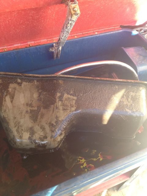 1992 Ford Bronco - A greasy oil pan is shown inside a red and blue container, with a hose visible in the background.