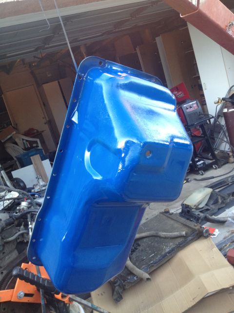 1992 Ford Bronco - Oil pan painted blue and suspended for work in a garage setting.