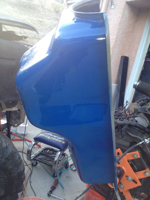 1992 Ford Bronco - A close-up view of a shiny blue vehicle fender, with mechanical components and tools scattered around the work area.