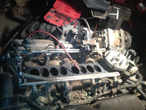 1992 Ford Bronco - Close-up of engine components, including a carburetor and distributor, with a toolbox nearby.