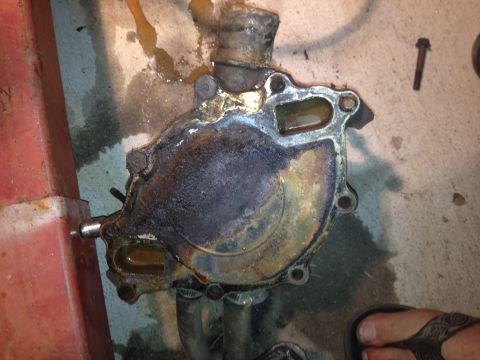 1992 Ford Bronco - A heavily corroded water pump sits on a concrete surface, showing signs of wear and tear.