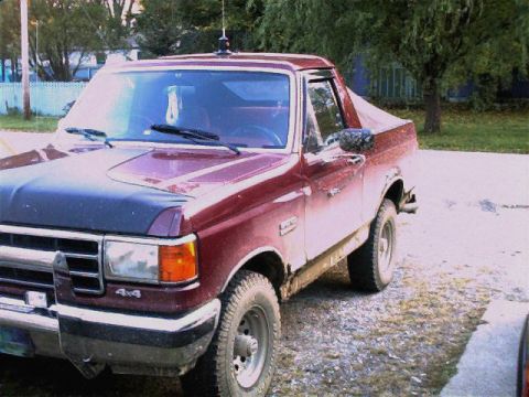 1990 Ford Bronco - This 1990 Ford Bronco is shown in a 3q front view, a red body with a contrasting black hood and 4x4 badging.