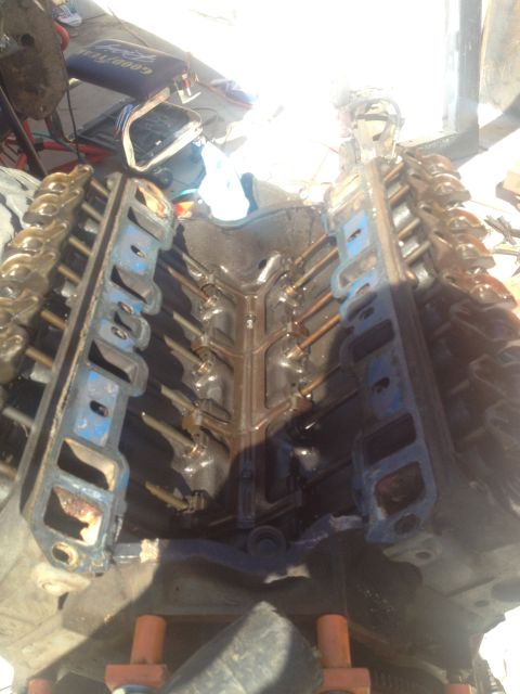 1992 Ford Bronco - Disassembled engine block with blue valve covers and exposed pushrods, likely undergoing repair or rebuild.