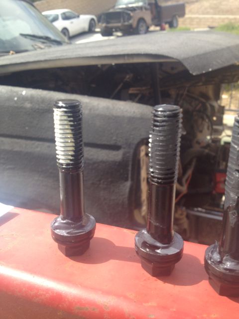 1992 Ford Bronco - Bolts with sealant are ready for installation, with a vehicle engine and other cars visible in the background.