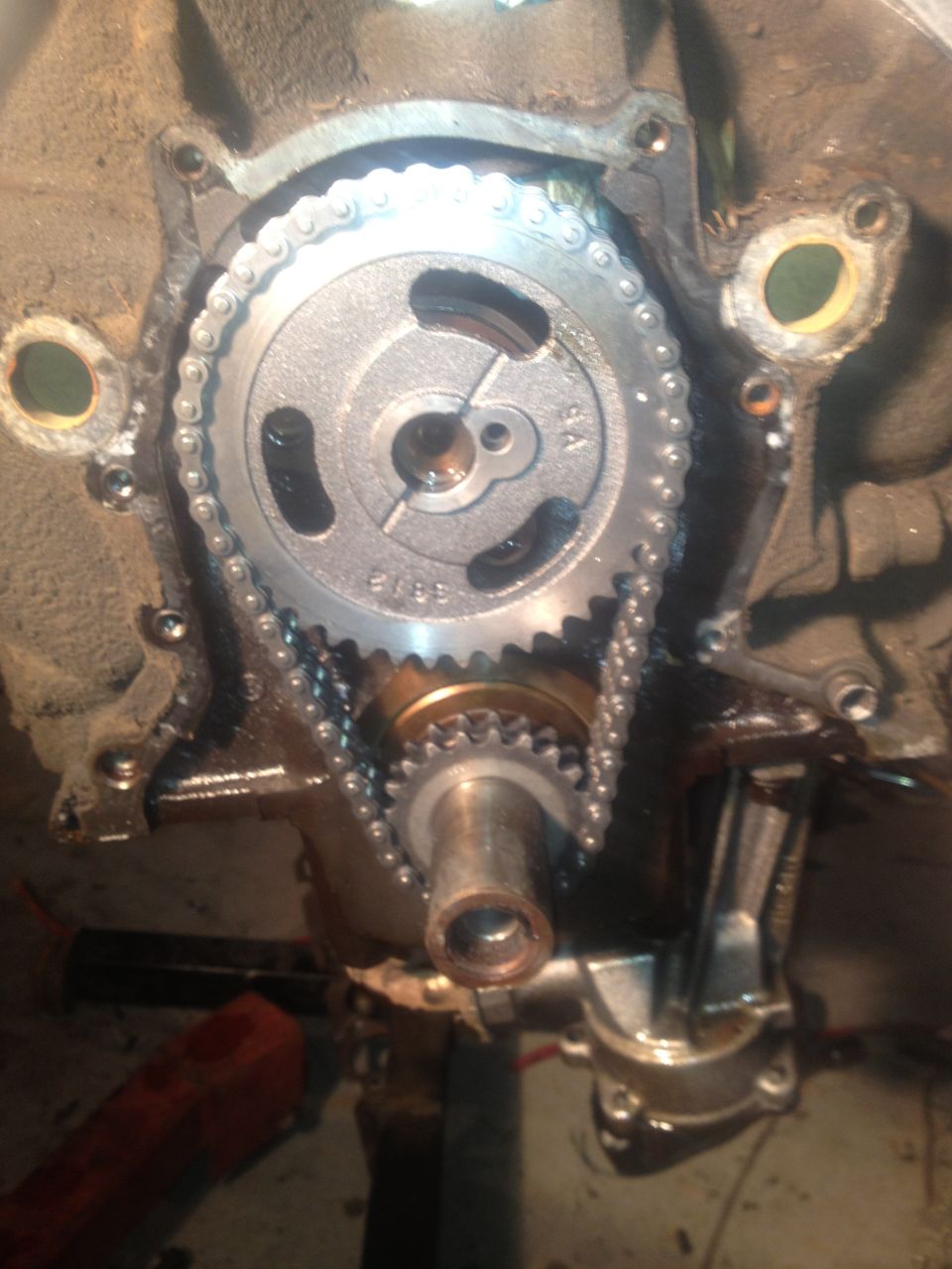 Close-up of engine timing chain and gears with part numbers visible on the gear