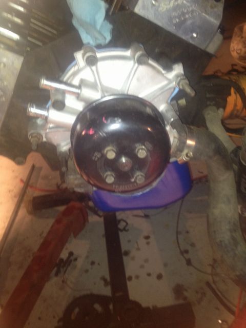 1992 Ford Bronco - Water pump assembly removed from engine, placed on a drip pan for service.