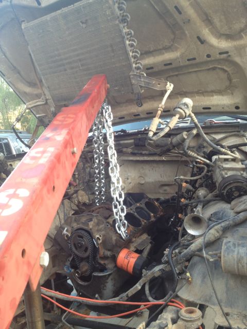 1992 Ford Bronco - The engine is being removed from the vehicle using an engine hoist and chains.